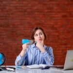 front-view-travel-agent-her-working-place-holding-credit-card-map-indoors-manager-worker-service-agency-operator-world-occupation-money-documents