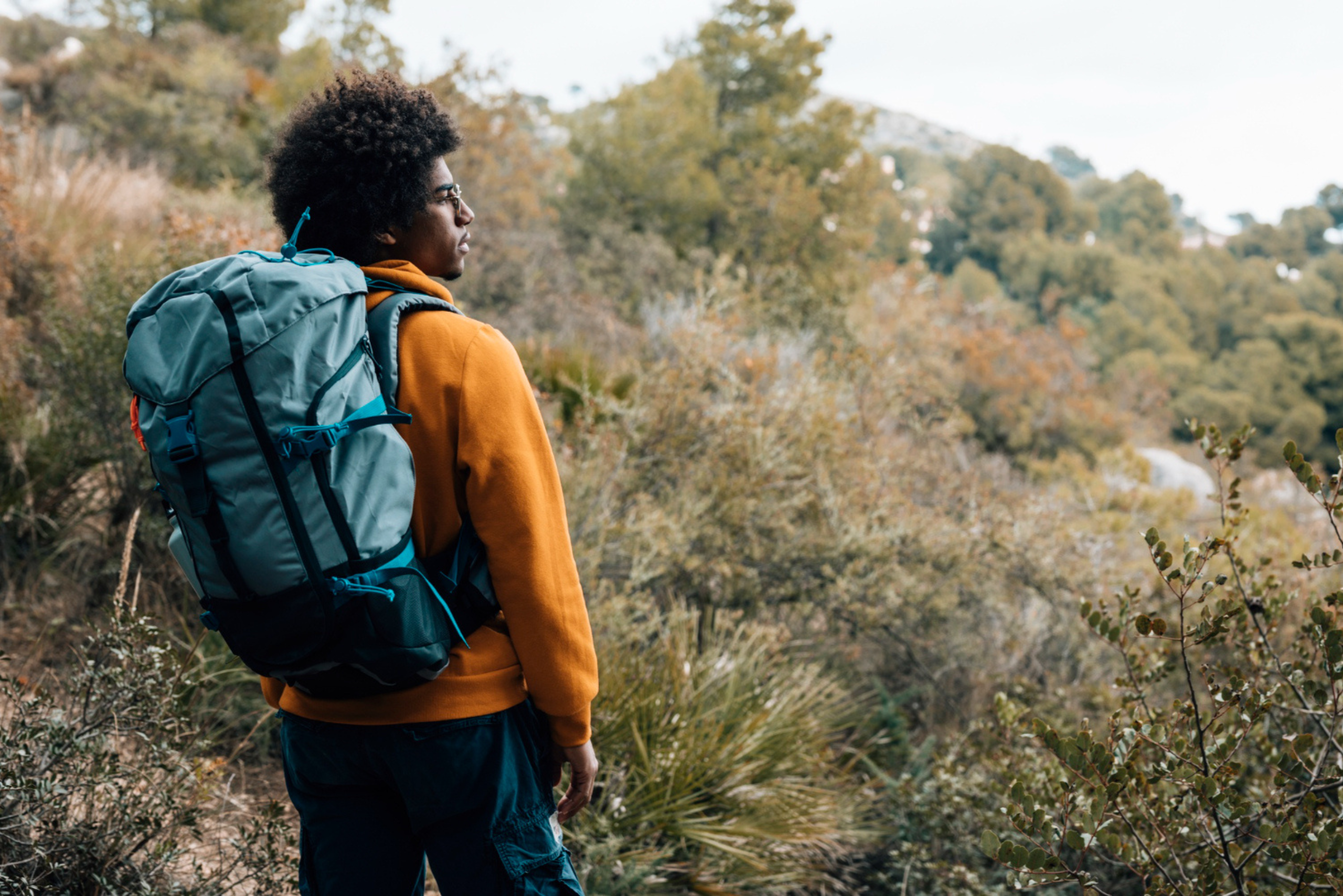An image showing a confident traveler in rugged terrain, carrying a travel bag and looking determined to navigate his environment.