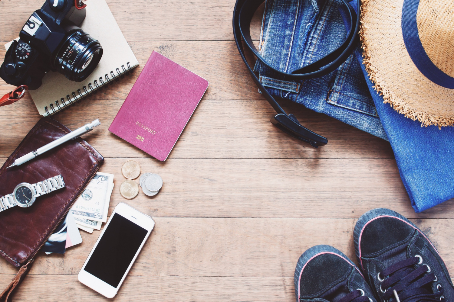An image showing some travelers' essentials such as footwear, wallet, clothes, and hat.
