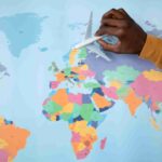 An image showing a person holding a small toy aeroplane over a colourful world map, symbolising travel and exploration.