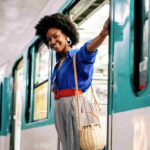 An image showing an African woman standing by the train door. 