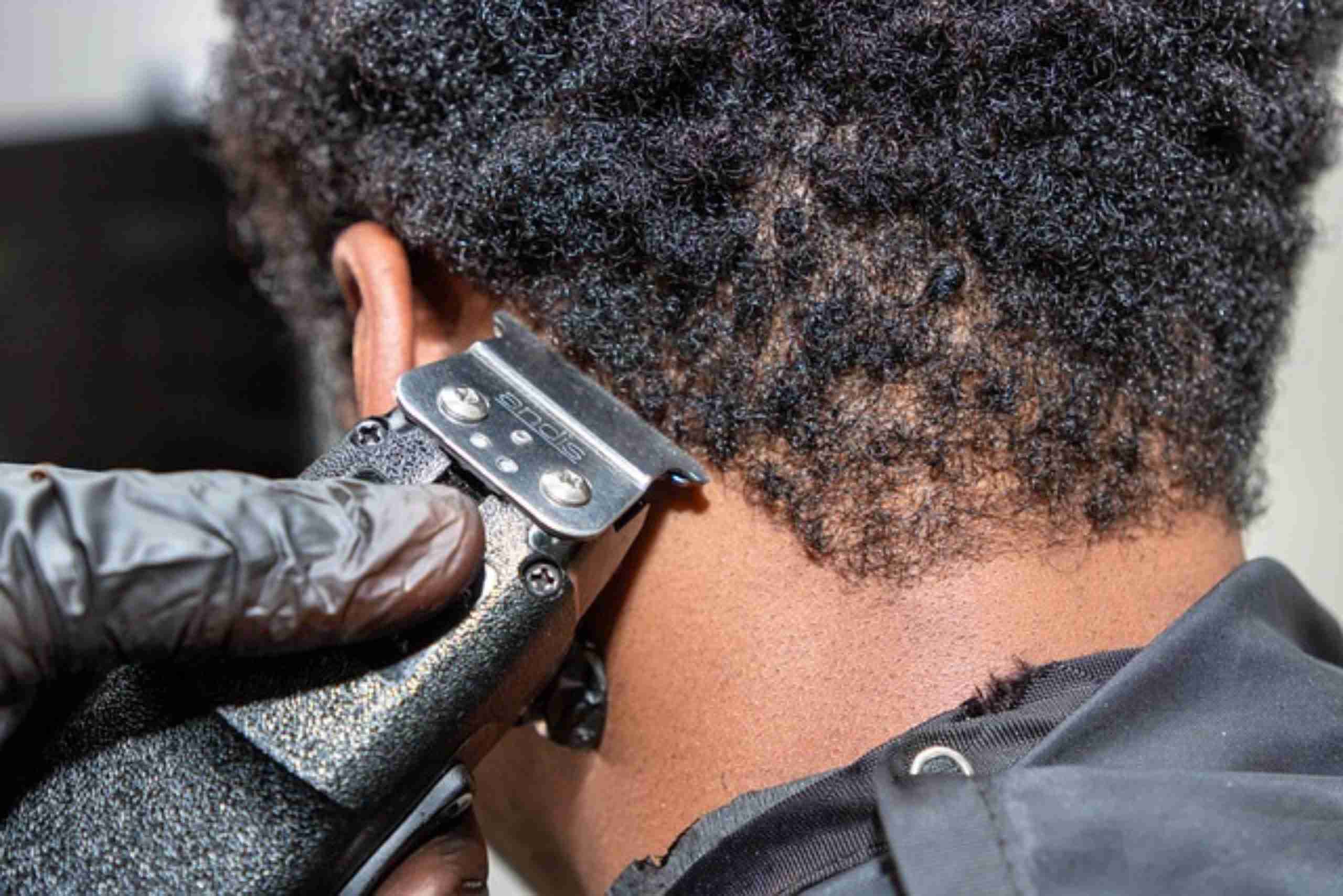 An image showing a migrant barber professionally cutting a client’s hair.