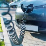 An image showing an Electric Vehicle being plugged at a charge station. 
