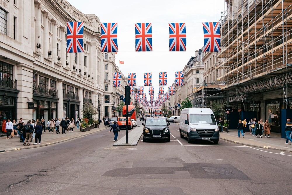 a busy street in the UK with cars and people walking the sidewalk