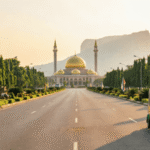 Abuja travel tips – wide empty boulevard leading to the golden-domed National Mosque with Zuma Rock at sunset and a keke tricycle