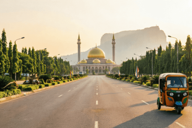 Abuja travel tips – wide empty boulevard leading to the golden-domed National Mosque with Zuma Rock at sunset and a keke tricycle