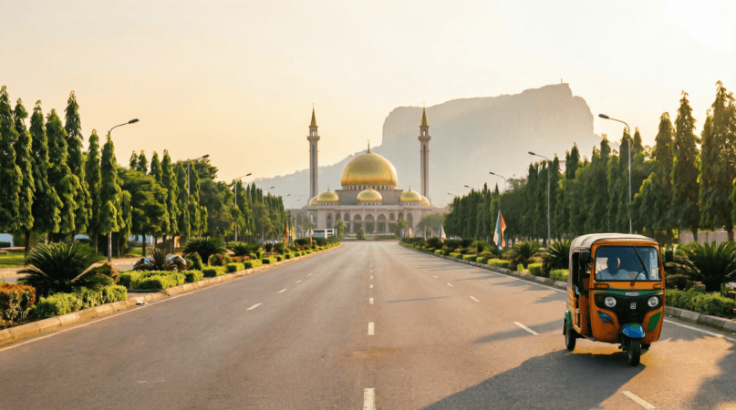 Abuja travel tips – wide empty boulevard leading to the golden-domed National Mosque with Zuma Rock at sunset and a keke tricycle