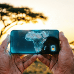 Traveler holding smartphone with digital Africa map and eSIM icon with African savanna background