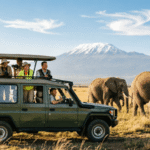 Open-roof safari vehicle on the golden savannah of Maasai Mara with elephants and Mount Kilimanjaro in the background, perfect for a Kenya safari guide for first-time visitors.